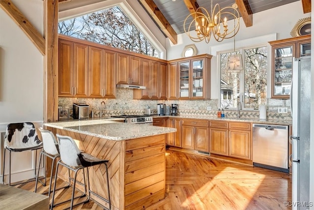 kitchen with kitchen peninsula, stainless steel appliances, pendant lighting, an inviting chandelier, and vaulted ceiling with beams