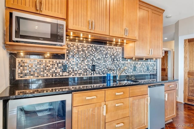 kitchen with backsplash, beverage cooler, dark stone counters, and sink