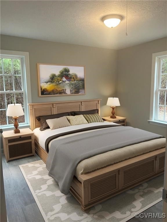 bedroom featuring hardwood / wood-style floors, multiple windows, an AC wall unit, and a textured ceiling