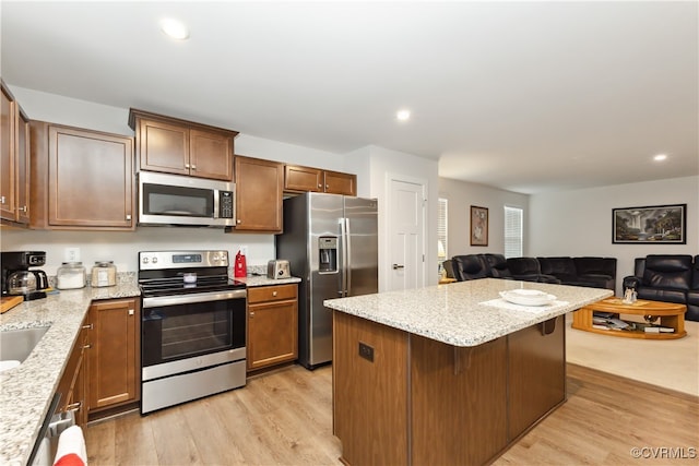 kitchen with a kitchen breakfast bar, light stone countertops, light hardwood / wood-style floors, and appliances with stainless steel finishes