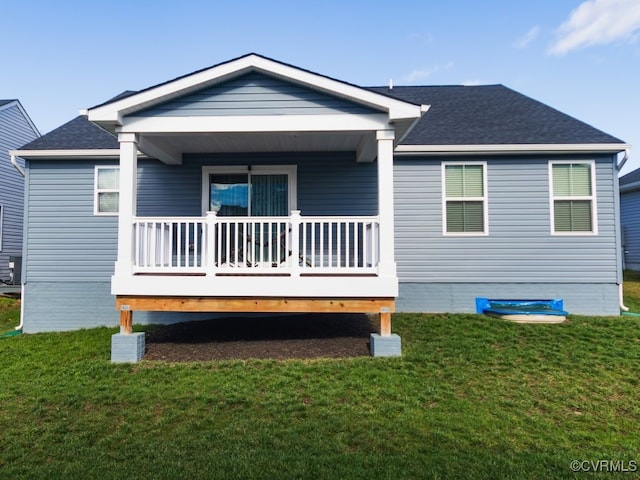 back of property with covered porch and a yard