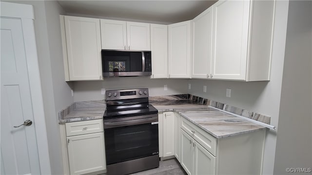 kitchen with white cabinetry, stainless steel appliances, and light stone counters