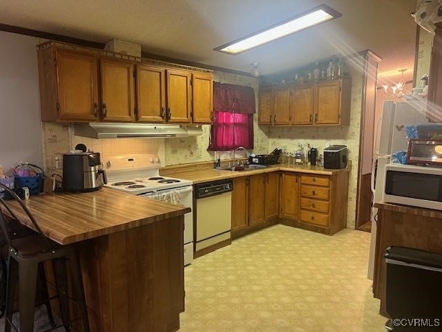 kitchen with kitchen peninsula, white appliances, sink, and crown molding