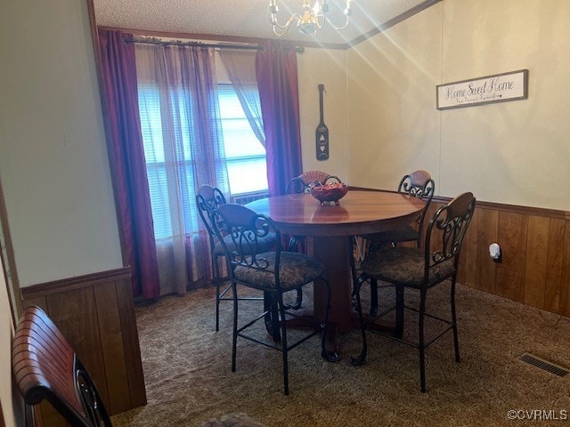 dining space with carpet, wooden walls, a textured ceiling, and a chandelier