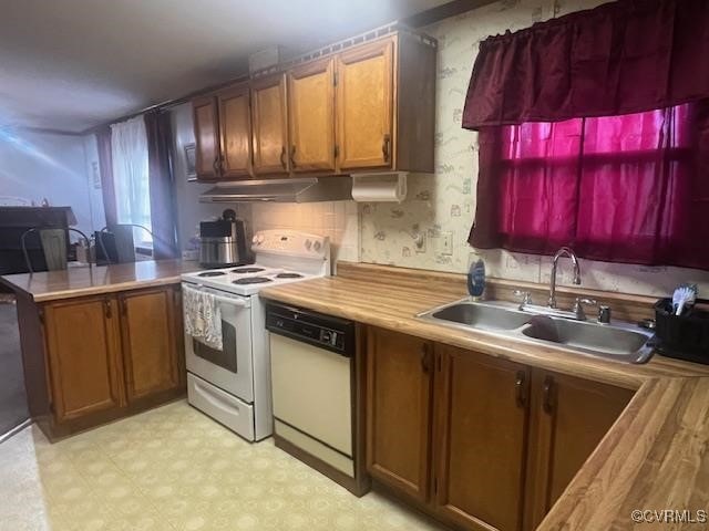 kitchen featuring kitchen peninsula, butcher block counters, sink, and white appliances