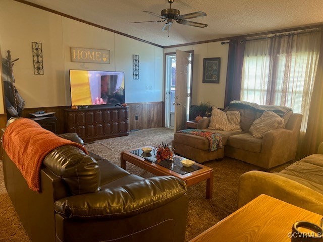 carpeted living room featuring crown molding, wood walls, a textured ceiling, and ceiling fan