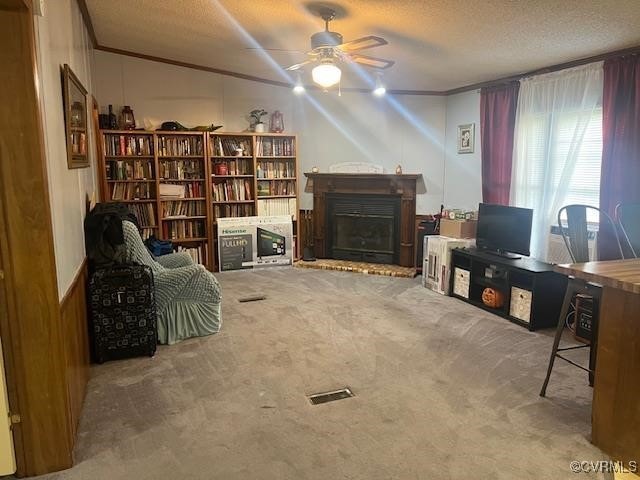 sitting room featuring ornamental molding, a textured ceiling, ceiling fan, and carpet floors