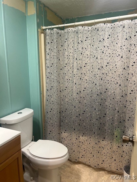 bathroom with toilet, a shower with curtain, vanity, and a textured ceiling