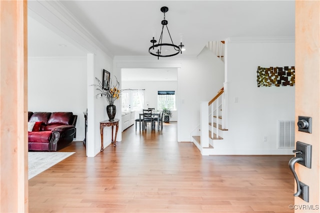 foyer featuring light hardwood / wood-style floors, a chandelier, and crown molding