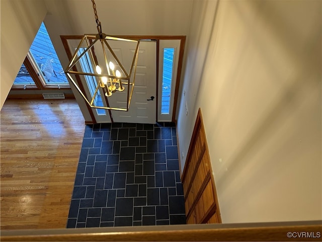 entrance foyer with dark tile patterned floors and a notable chandelier