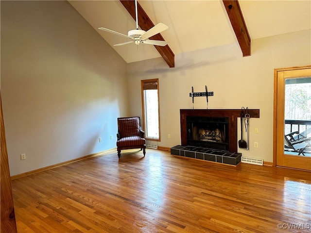 unfurnished room with high vaulted ceiling, hardwood / wood-style flooring, beamed ceiling, a tile fireplace, and ceiling fan