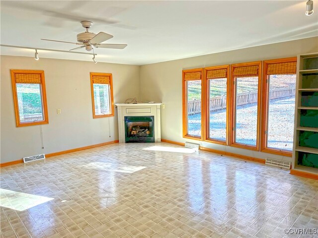 unfurnished living room featuring ceiling fan, plenty of natural light, and rail lighting