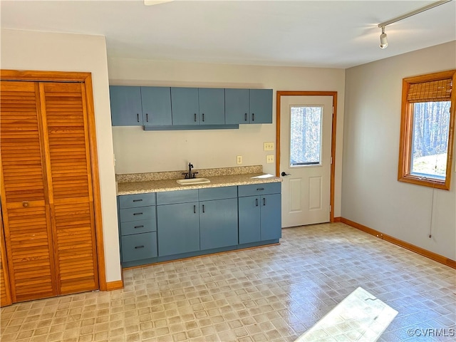 kitchen with blue cabinetry, track lighting, and sink