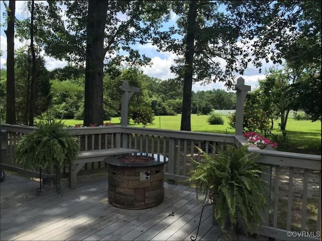 wooden terrace featuring a yard and a fire pit