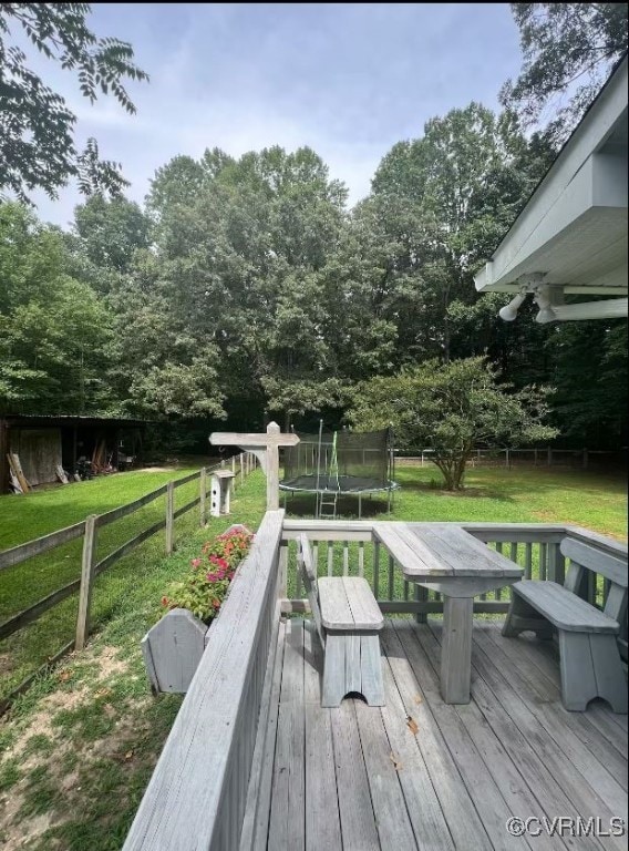 wooden deck with a yard and a trampoline