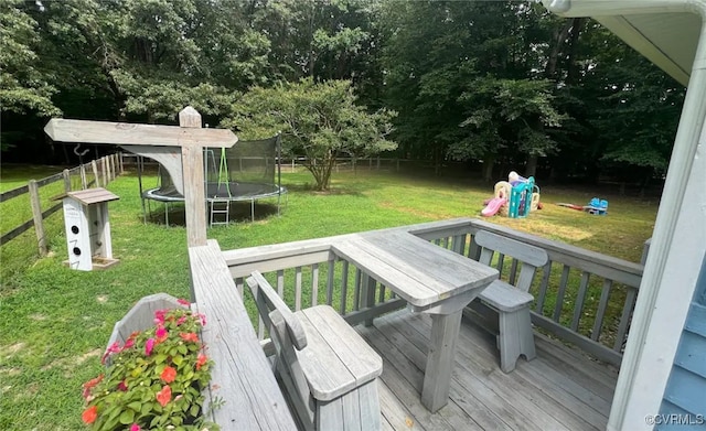 wooden deck with a playground, a trampoline, and a yard