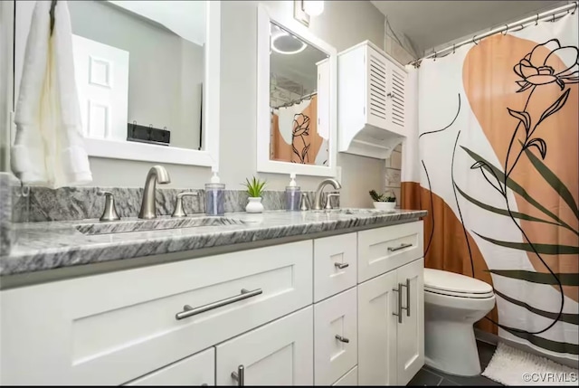 bathroom with toilet, vanity, and tile patterned flooring