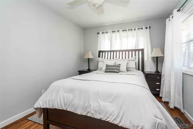 bedroom featuring dark hardwood / wood-style floors, ceiling fan, and multiple windows