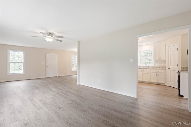 empty room with ceiling fan, sink, and light hardwood / wood-style floors