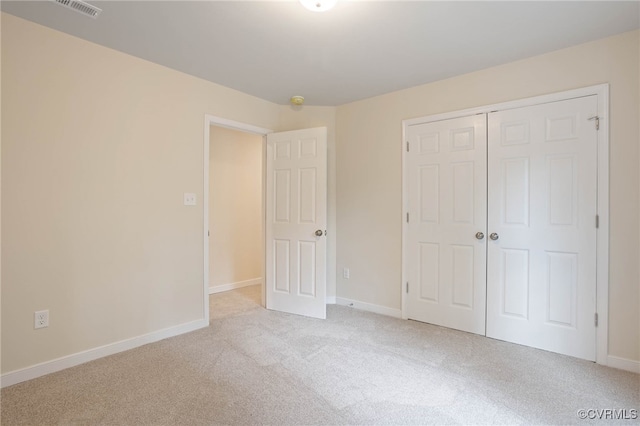 unfurnished bedroom featuring light colored carpet and a closet