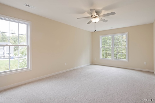 unfurnished room with a wealth of natural light, carpet floors, and ceiling fan