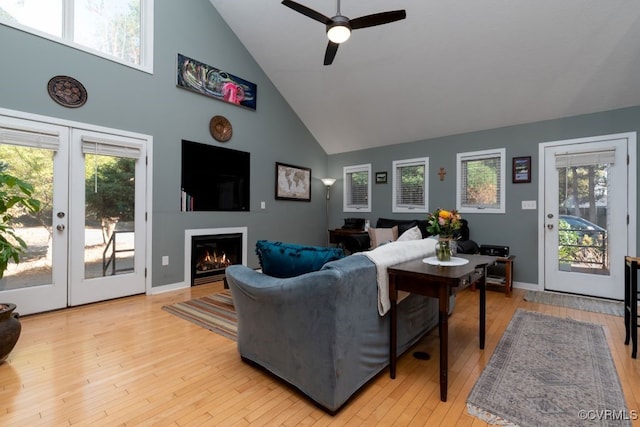 living room with light hardwood / wood-style floors, high vaulted ceiling, a healthy amount of sunlight, and french doors