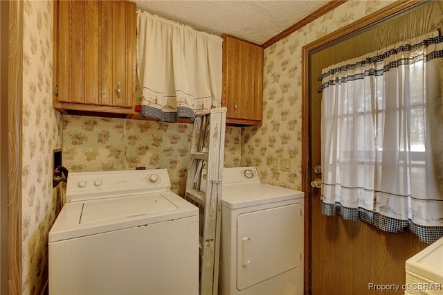 clothes washing area with washer and dryer, ornamental molding, a textured ceiling, and cabinets