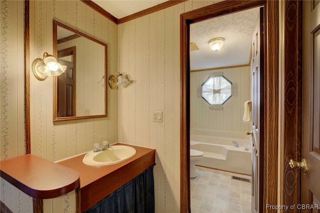 bathroom with a textured ceiling, toilet, a bathtub, vanity, and ornamental molding