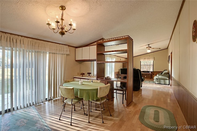 dining space with a textured ceiling, ceiling fan with notable chandelier, light hardwood / wood-style floors, and vaulted ceiling