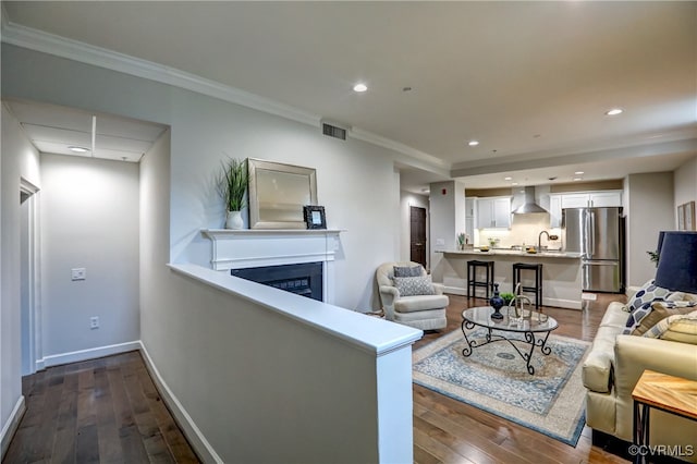 living room with dark wood-type flooring, sink, and ornamental molding