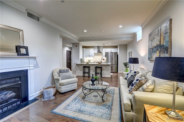 living room with dark hardwood / wood-style flooring, sink, and crown molding