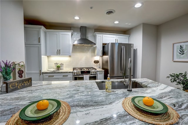 kitchen with white cabinetry, wall chimney exhaust hood, high quality appliances, and sink