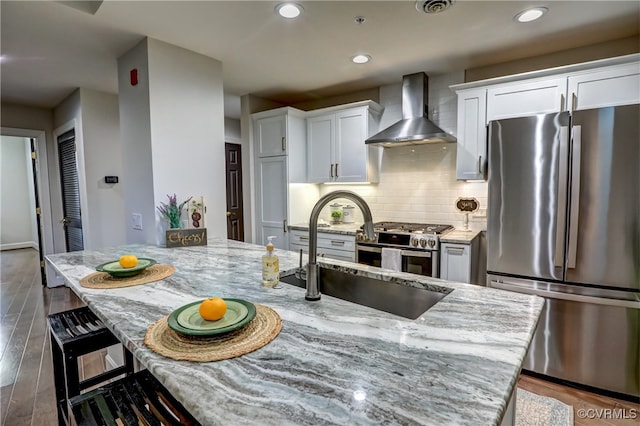 kitchen featuring stainless steel appliances, wall chimney exhaust hood, white cabinets, and dark hardwood / wood-style floors