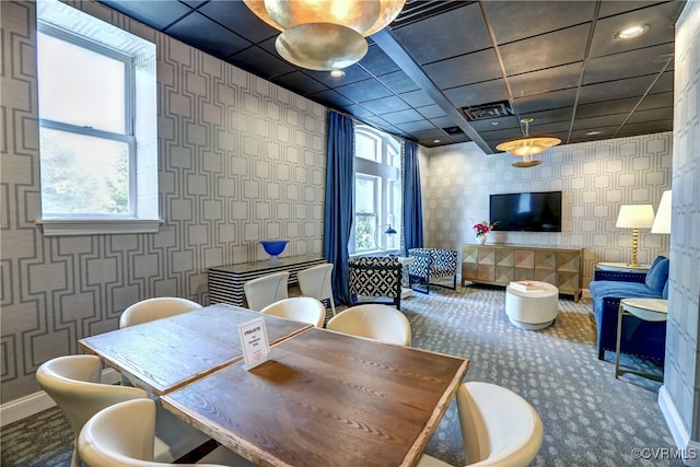 carpeted dining space with a healthy amount of sunlight and a drop ceiling