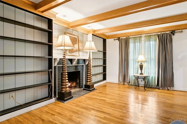 unfurnished living room featuring a fireplace, light wood-type flooring, and beamed ceiling