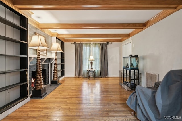 sitting room featuring beam ceiling, a fireplace, and hardwood / wood-style floors