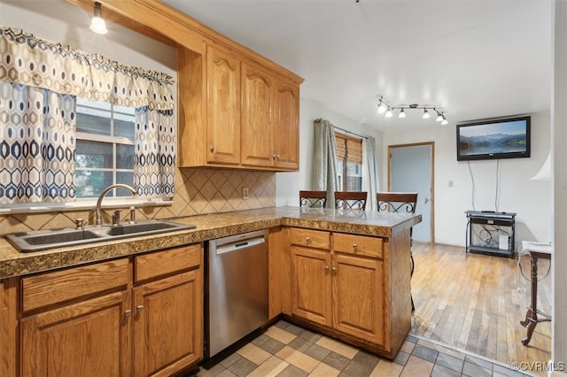 kitchen with sink, stainless steel dishwasher, kitchen peninsula, light hardwood / wood-style floors, and decorative backsplash