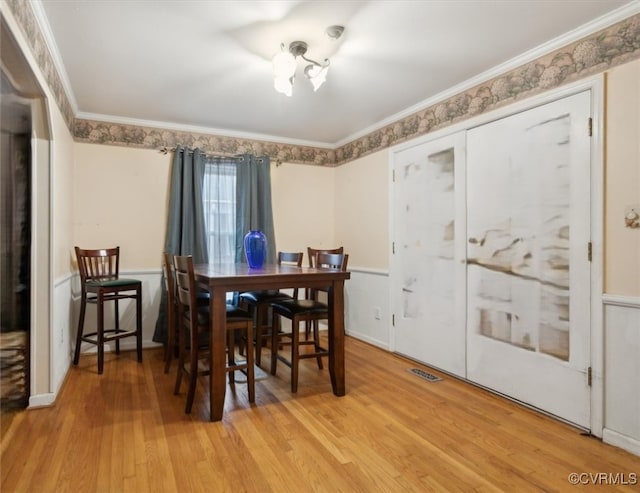 dining area with light wood-type flooring and ornamental molding