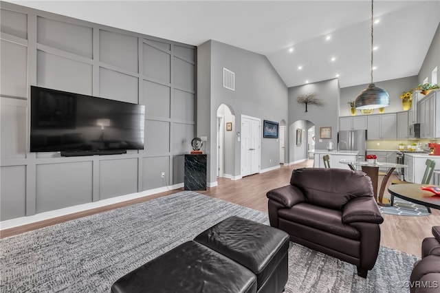 living room with high vaulted ceiling and hardwood / wood-style floors