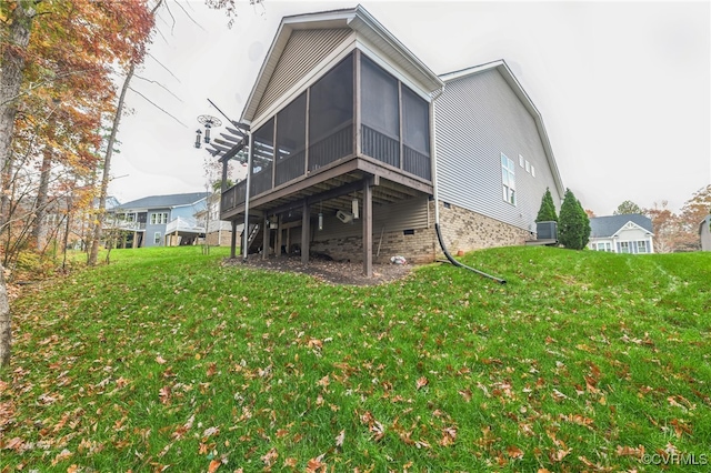 back of property featuring a sunroom and a lawn