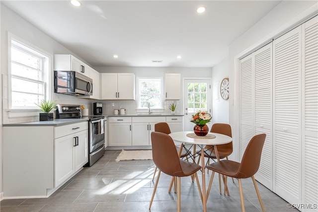 kitchen with white cabinetry, sink, backsplash, and stainless steel appliances