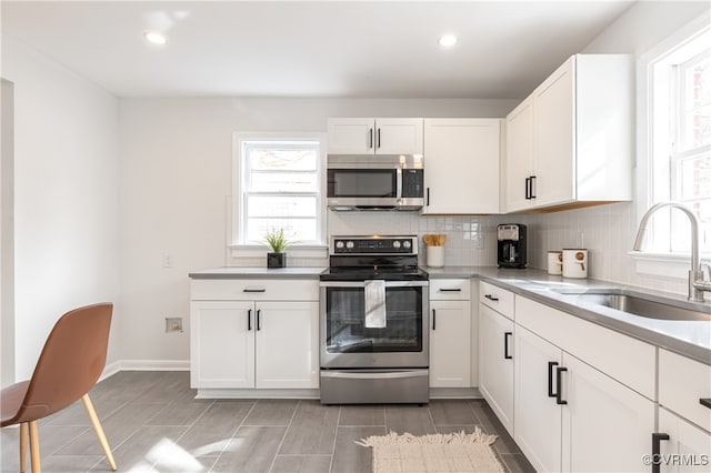 kitchen with white cabinets, appliances with stainless steel finishes, tasteful backsplash, and sink