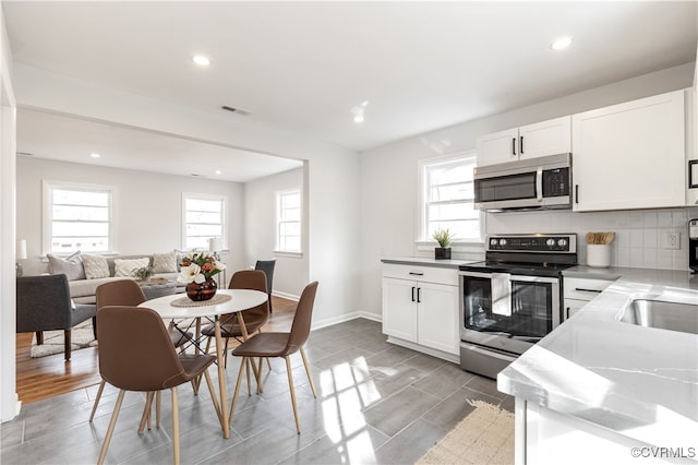 kitchen featuring decorative backsplash, white cabinetry, light hardwood / wood-style floors, and stainless steel appliances