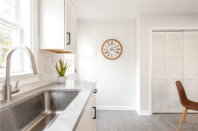 kitchen featuring decorative backsplash, white cabinetry, and sink