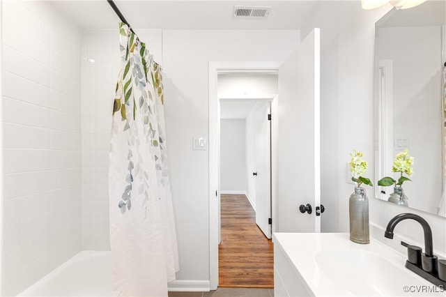 bathroom featuring hardwood / wood-style floors, vanity, and shower / tub combo