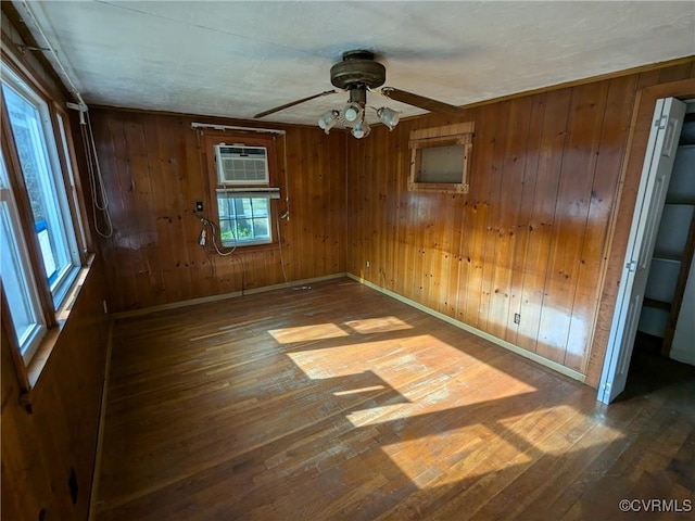 spare room with hardwood / wood-style flooring, plenty of natural light, wood walls, and ceiling fan