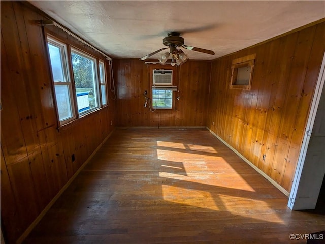 empty room with wood-type flooring, wood walls, and plenty of natural light