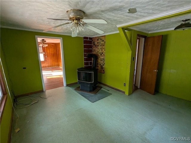 unfurnished living room featuring ceiling fan, crown molding, a textured ceiling, and a wood stove