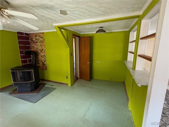 unfurnished living room with crown molding, a wood stove, ceiling fan, and a textured ceiling