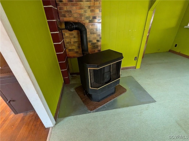 interior details featuring carpet floors, a wood stove, and wood walls